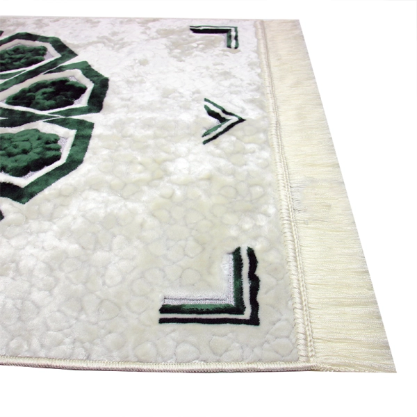 white prayer mat with an emerald green pattern